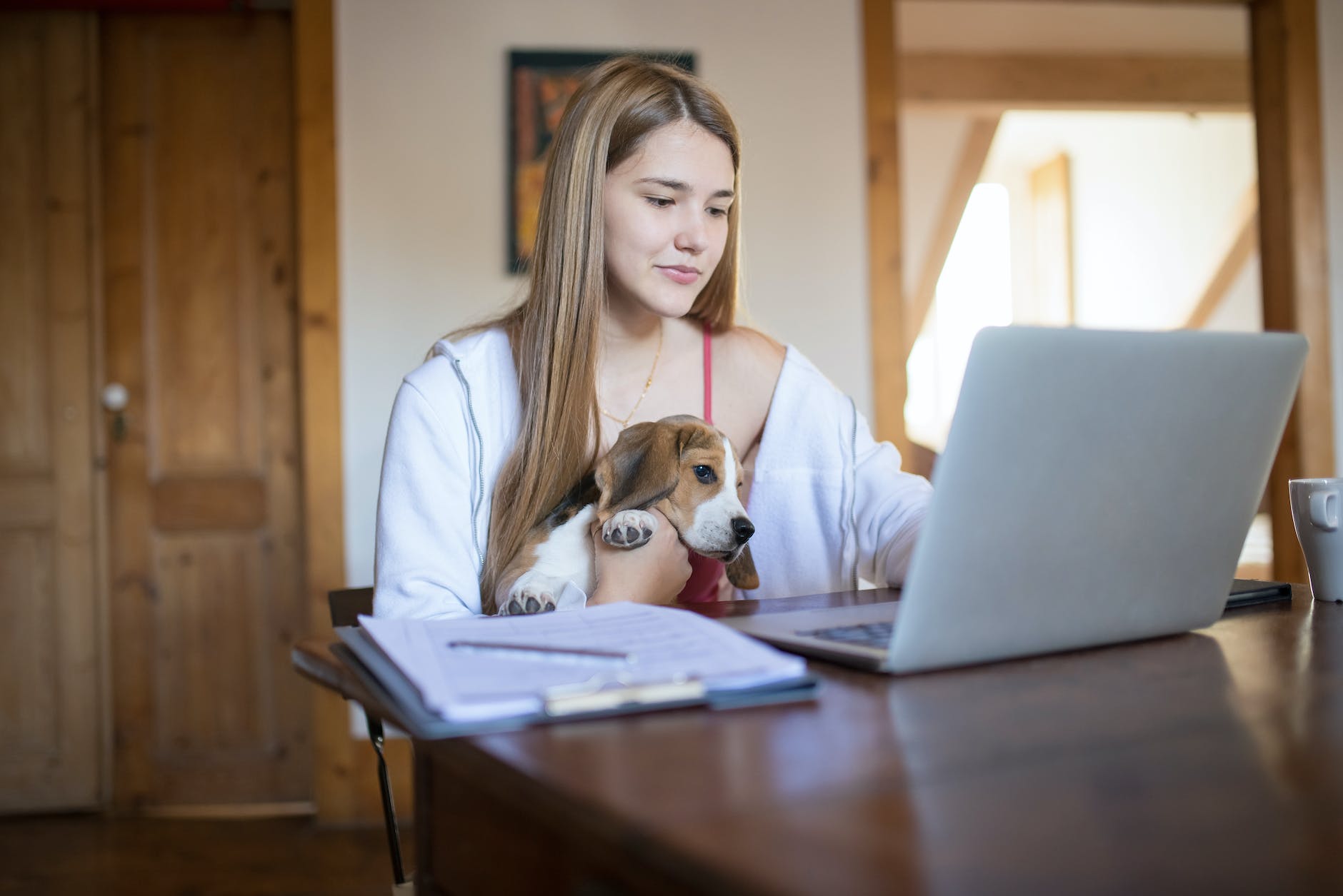 Woman using a laptop with a dog on her lap